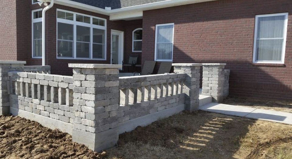 Paver stone balustrade wall installation at brick home patio